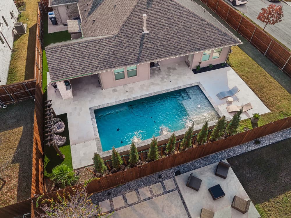 Aerial view of a modern backyard with a swimming pool, lounge chairs, and landscaped garden.